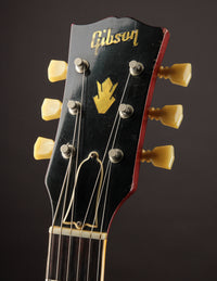 Gibson guitar headstock with tuning pegs on a dark background