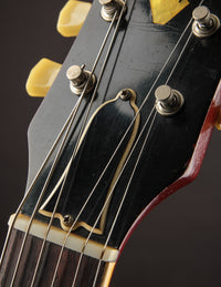 Close-up of a guitar headstock with tuning pegs and strings.