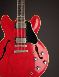 Red electric guitar with a black pickguard on a dark background