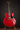 Red electric guitar on a stand against a dark background