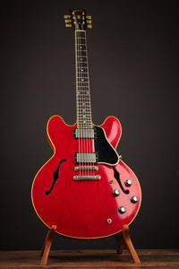 Red electric guitar on a stand against a dark background