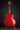 Red electric guitar on a stand against a dark background