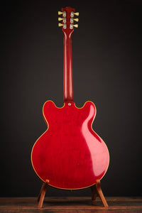 Red electric guitar on a stand against a dark background