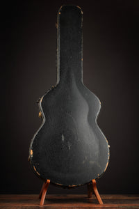 Vintage guitar case on a stand against a dark background