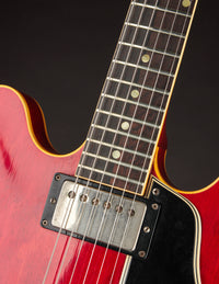 Close-up of a red electric guitar's neck and body on a black background