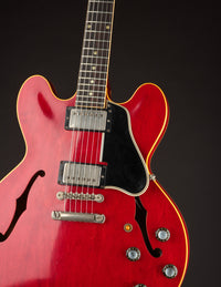 Red electric guitar with a black pickguard on a dark background