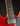 Close-up of a red electric guitar with a black pickguard on a dark background