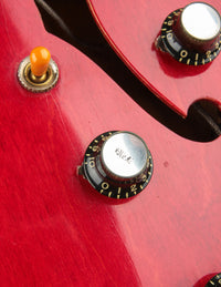 Close-up of a red electric guitar with control knobs 