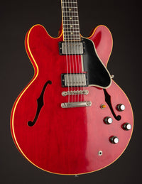 Red electric guitar with a black pickguard on a dark background