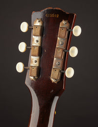 Close-up of a guitar headstock with tuning pegs on a dark background
