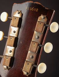 Close-up of a guitar headstock with tuning pegs on a dark background