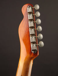 Close-up of a guitar headstock with tuning pegs on a dark background