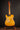 Telecaster guitar with a blonde finish on a stand against a dark background, back view 