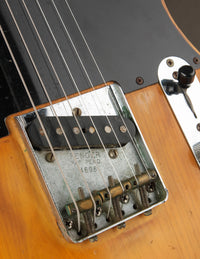Close-up of a guitar bridge with 'Fender' branding on a wooden guitar body.