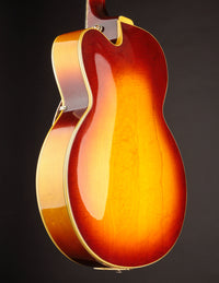 Back view of a vintage Johnny Smith archtop guitar with a sunburst finish on a dark background