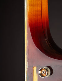 Close up of finish wear on the neck of a Gibson Johnny Smith archtop guitar with a sunburst finish on a dark background