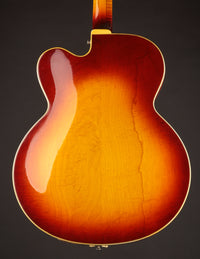Back view of a vintage Johnny Smith archtop guitar with a sunburst finish on a dark background