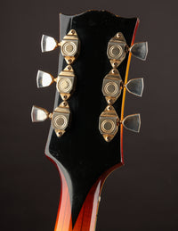 Close-up of a guitar headstock with tuning pegs on a dark background