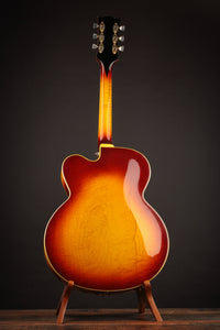 Vintage Johnny Smith archtop guitar with a sunburst finish on a stand against a dark background
