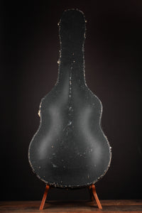 Vintage guitar case on a stand against a dark background 