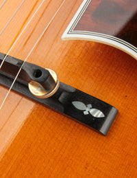 Close up of decorative inlay on the bridge of a vintage Johnny Smith archtop guitar with a sunburst finish