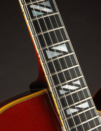 Close-up of a Gibson archtop guitar neck against a dark background