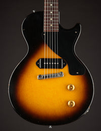 Vintage electric guitar with sunburst finish and black pickguard on a dark background