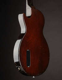 Vintage electric guitar with sunburst finish and black pickguard on a dark background, back/side view 