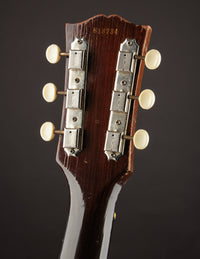 Close-up of a guitar headstock with tuning pegs on a dark background