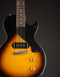 Vintage electric guitar with sunburst finish and black pickguard on a dark background