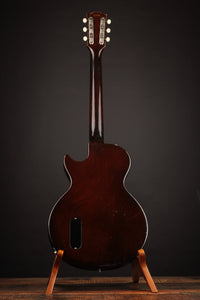 Acoustic guitar on a stand against a dark background