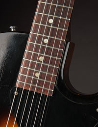 Close-up of a guitar's fretboard with dark wood and white inlays on a black background.