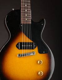 Vintage electric guitar with sunburst finish and black pickguard on a dark background