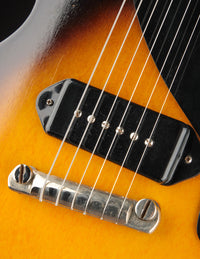 Close-up of a guitar's bridge and strings with a sunburst finish.