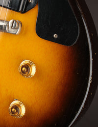 Close-up of a guitar's body with a sunburst finish and gold knobs