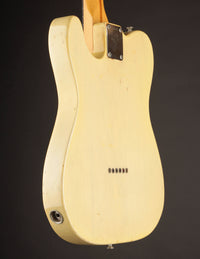 Back view of a cream-colored electric guitar on a black background