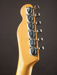 Close-up of a guitar headstock with tuning pegs on a dark background