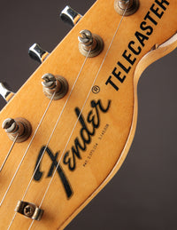Fender Telecaster headstock with branding on a dark background