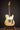 White electric guitar on a stand against a dark background