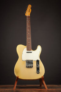 White electric guitar on a stand against a dark background