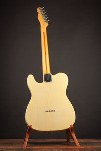 White electric guitar on a stand against a dark background