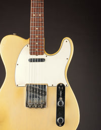 Vintage electric guitar with a blonde finish on a dark background