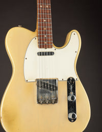 Vintage electric guitar with a blonde finish on a dark background