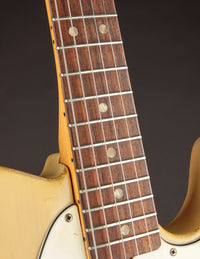 Close-up of a guitar neck and body on a dark background