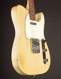 Vintage electric guitar with a blonde finish on a dark background