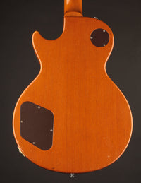 Back view of an electric guitar with a dark brown finish on a black background