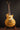 Gold electric guitar on a stand against a dark background
