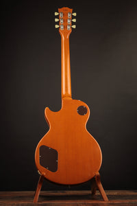 Back view of an electric guitar on a stand against a dark background
