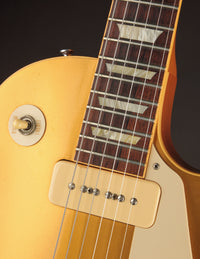 Close-up of a guitar's neck and pickup with a dark background