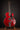 Red electric guitar on a stand against a dark background